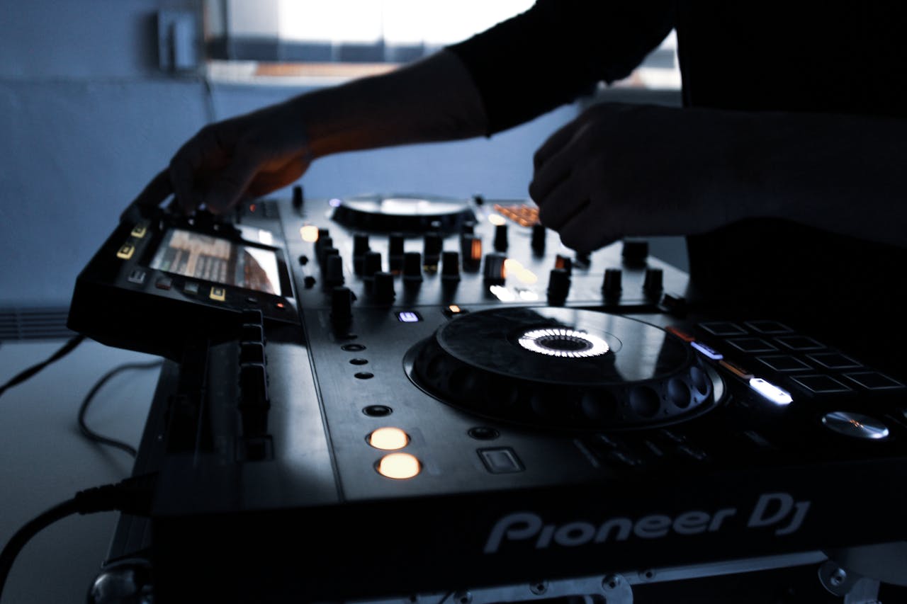 Close-up of DJ equipment in action during a mixing session in a dimly lit room.